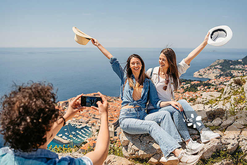 年轻男性朋友在杜布罗夫尼克高处拍摄两个女性朋友图片素材