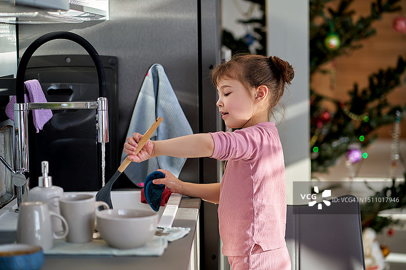 穿着粉色套装的女孩在洗碗图片素材