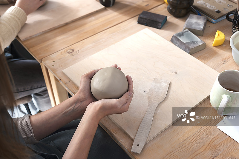 女人用手捏陶土，陶艺工坊课程，制作陶瓷餐具是一项受欢迎的爱好。图片素材