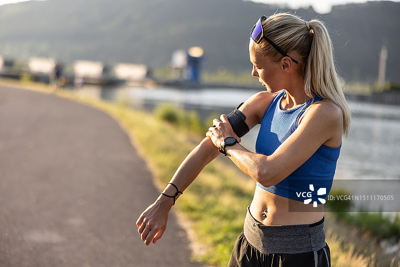 年轻女运动员跑步前将智能手机壳放在肩上图片素材