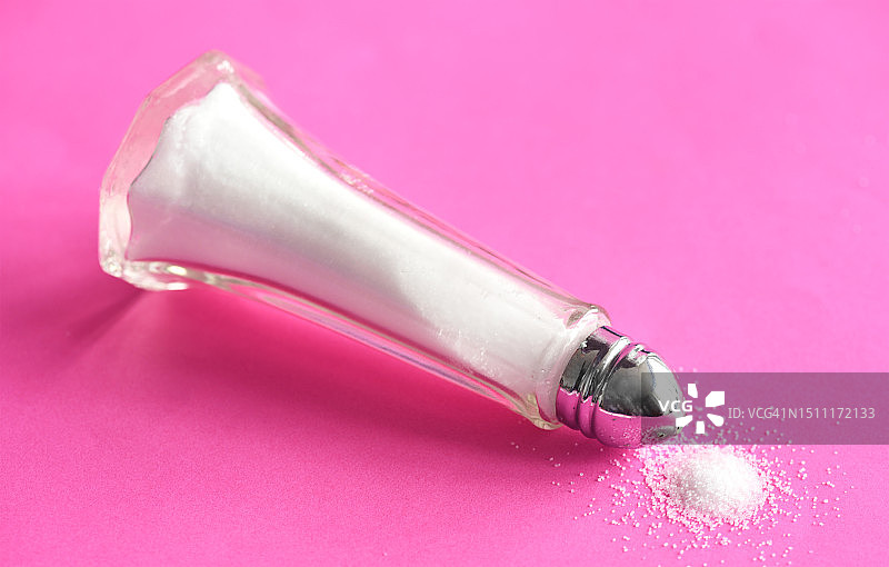 粉色布上的盐罐和洒落的盐图片素材