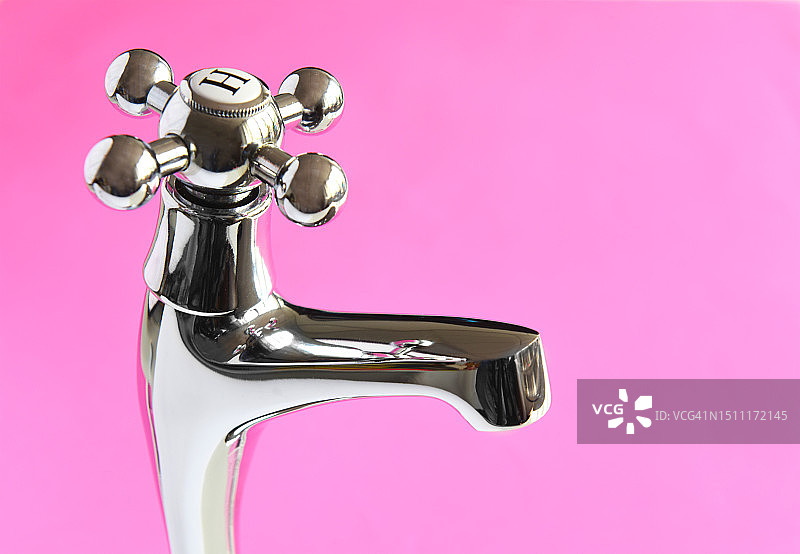 粉色背景上的热水龙头图片素材