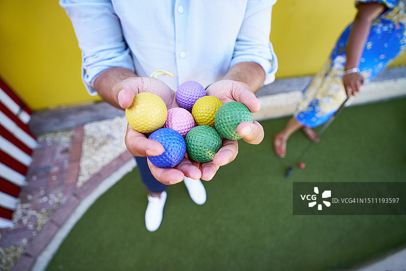 男人手持彩色高尔夫球图片素材