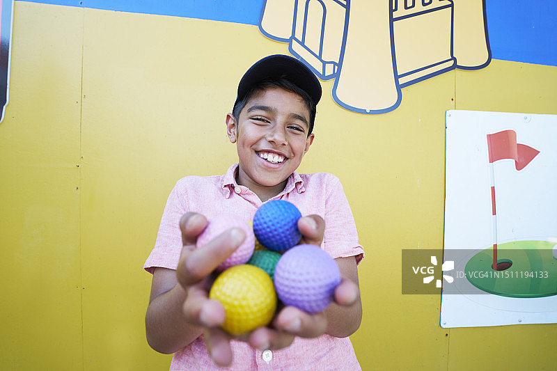 男孩在迷你高尔夫球场手拿彩色高尔夫球图片素材