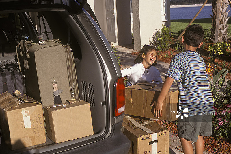 男孩和女孩帮忙搬箱子到户外新家图片素材