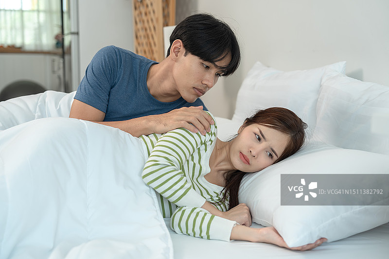 激烈的争吵：女人坐在床上生气，男人试图劝说图片素材