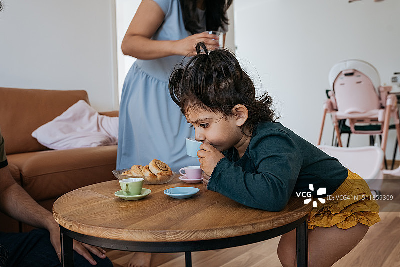 小孩子在客厅里用杯子喝东西图片素材