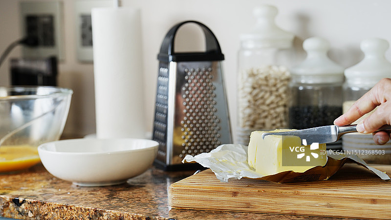 女性的手用刀从桌子上的一块黄油中切下新鲜黄油图片素材