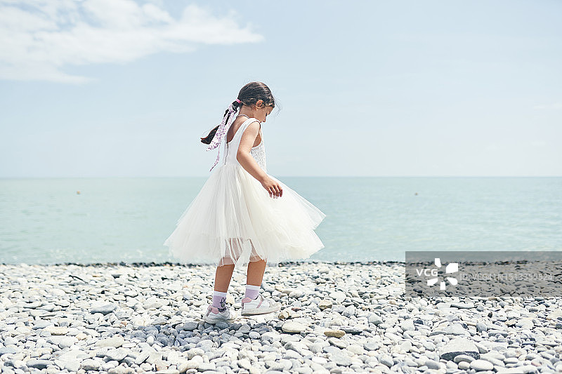 在海边穿着白色蓬松连衣裙的快乐女孩图片素材