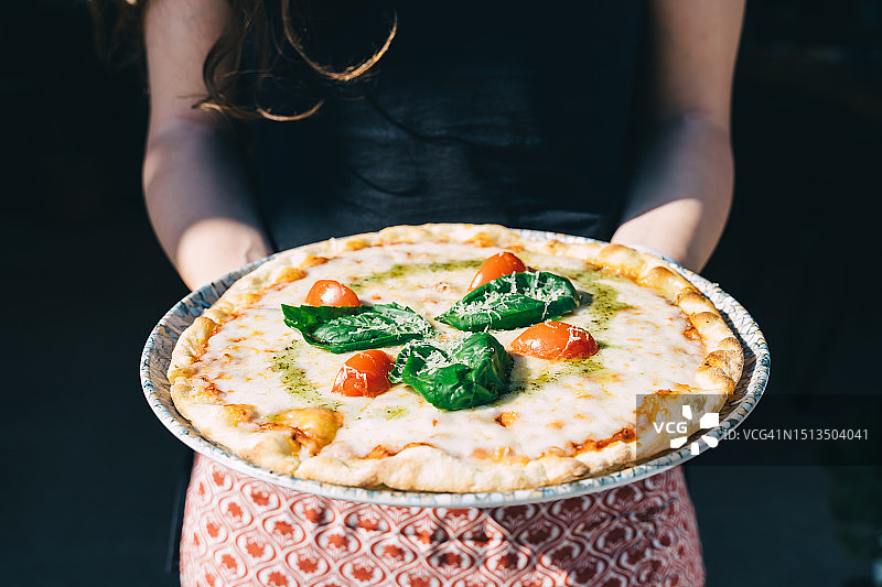 女士手中的玛格丽特披萨特写图片素材