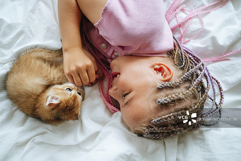 微笑的女孩在床上和猫玩耍图片素材
