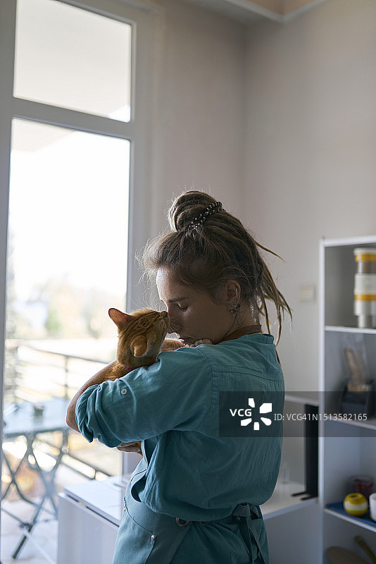 年轻女工匠在工作室拥抱猫图片素材