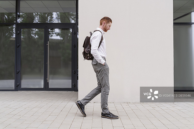 背着背包走在办公室外的商人图片素材