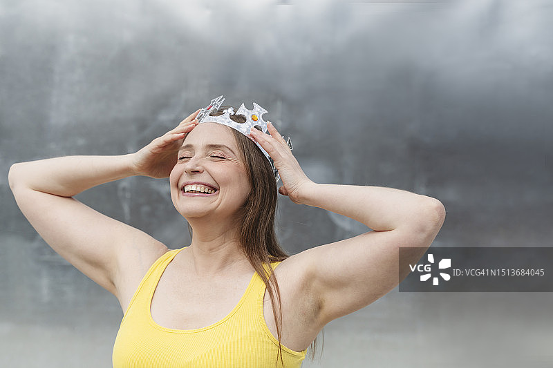 快乐的女人在墙前戴着皇冠图片素材