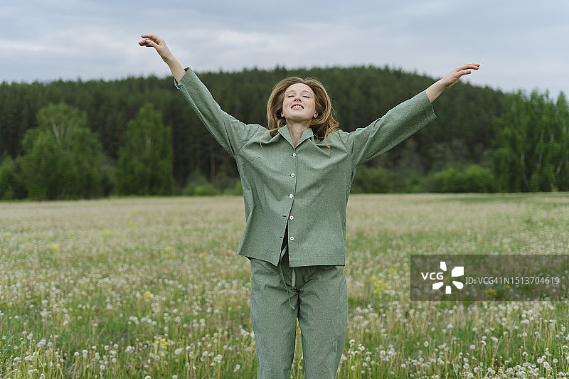 在蒲公英田中张开双臂的年轻女人图片素材