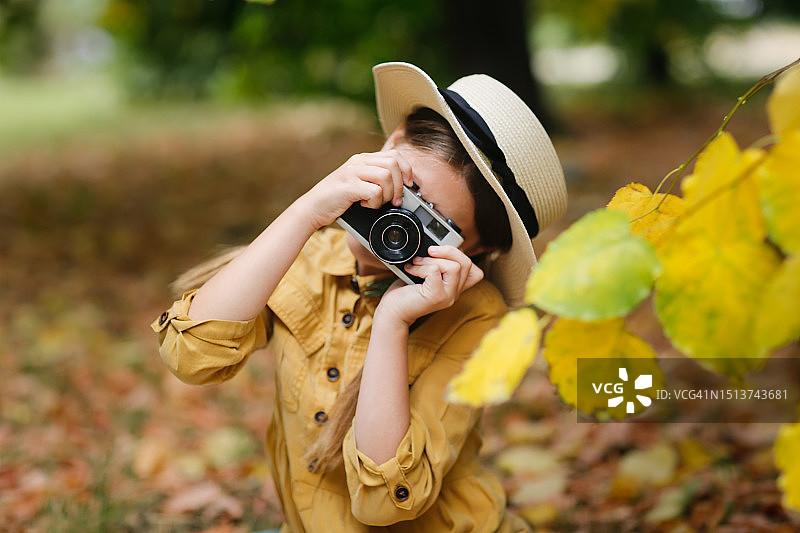 戴柳条帽和复古相机扎辫子的女孩的真实肖像图片素材