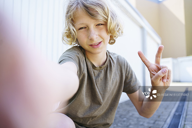 在车库外比“V”字手势的金发男孩图片素材