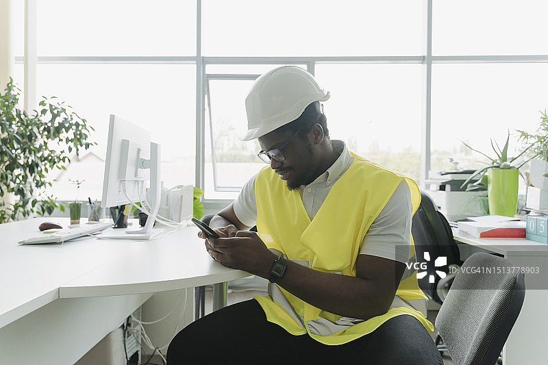 穿着反光衣服在办公桌旁发短信的商人图片素材
