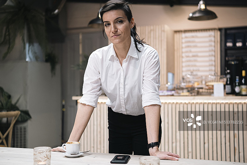 在咖啡馆靠在桌子上的自信女商人图片素材