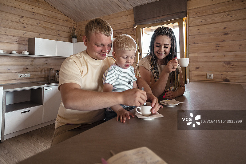 儿子和父母在家中厨房餐桌旁喝咖啡图片素材