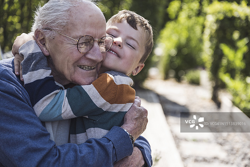 快乐的男孩在后院拥抱爷爷图片素材