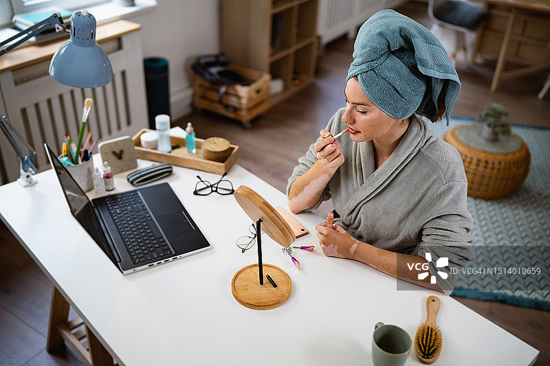 面部患有白癜风和痤疮的女人涂唇彩图片素材
