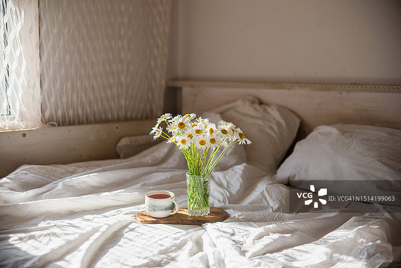 白色棉床单上雏菊花束的温柔早晨构图图片素材