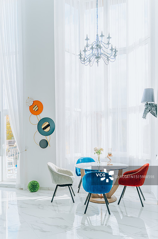 白色阁楼公寓的现代室内设计，桌子配彩色椅子，靠着大窗户图片素材