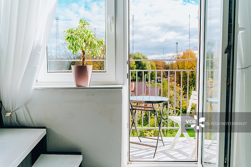 在家中阳台享受城市休闲，阳台上摆放着桌椅，舒适的现代公寓内景，有台阶和室内植物图片素材