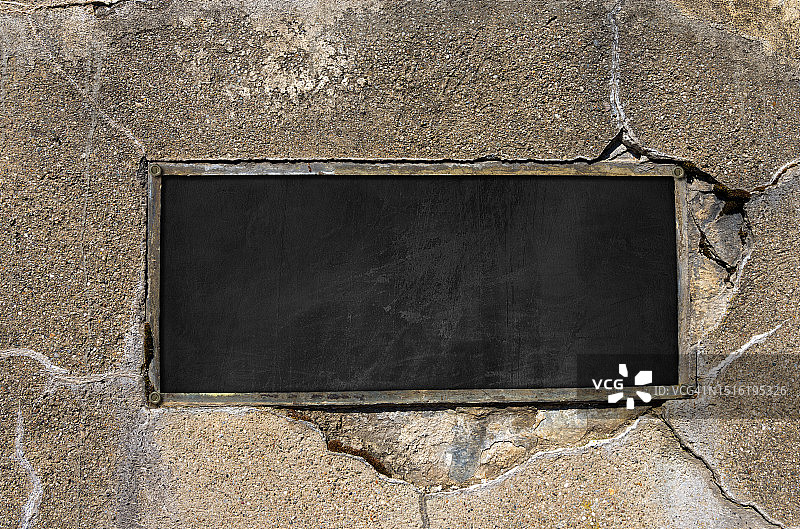 混凝土墙上的金属矩形框空黑板图片素材