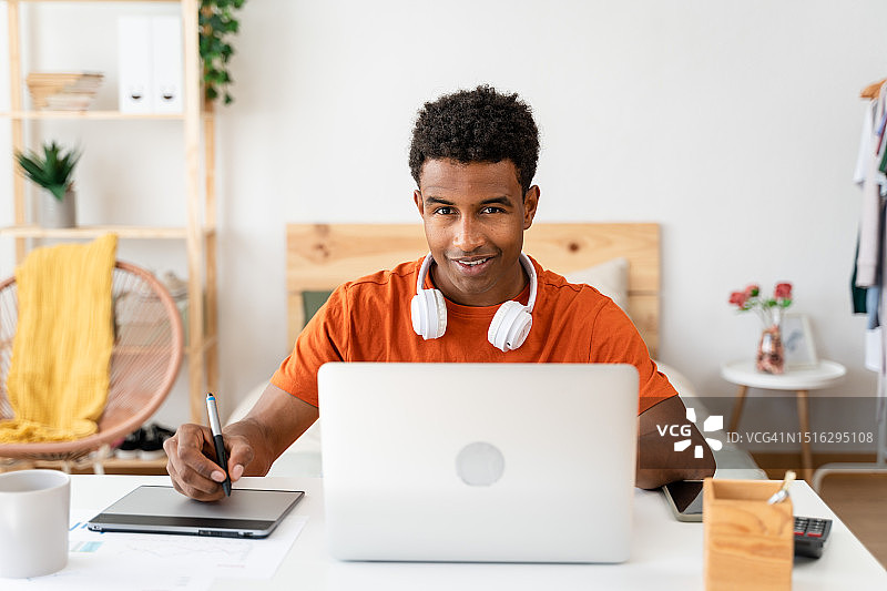 黑人男子在使用笔记本电脑时做笔记图片素材