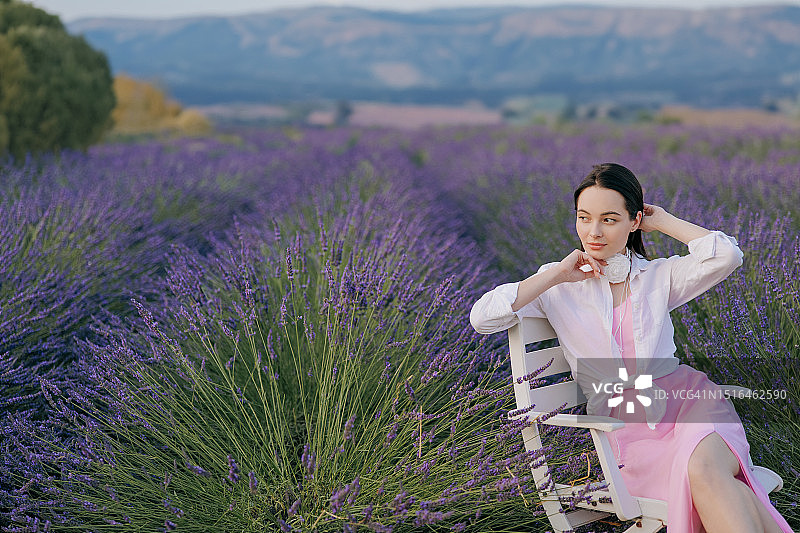 年轻女人在盛开的薰衣草中的扶手椅上休息，享受着它图片素材