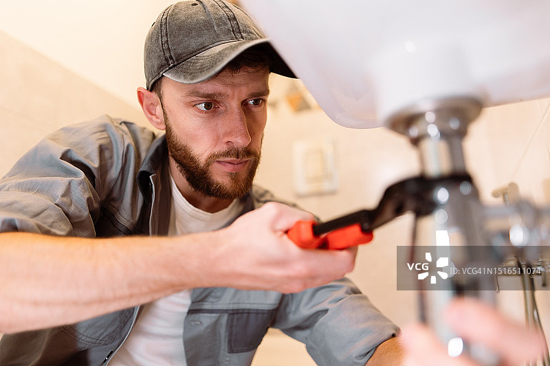 水管工用扳手仔细修理水槽的泄漏图片素材