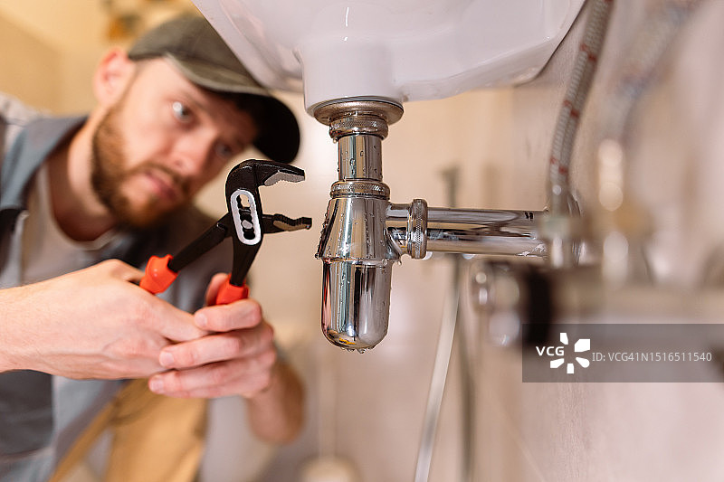 水管工用扳手仔细修理水槽的泄漏图片素材