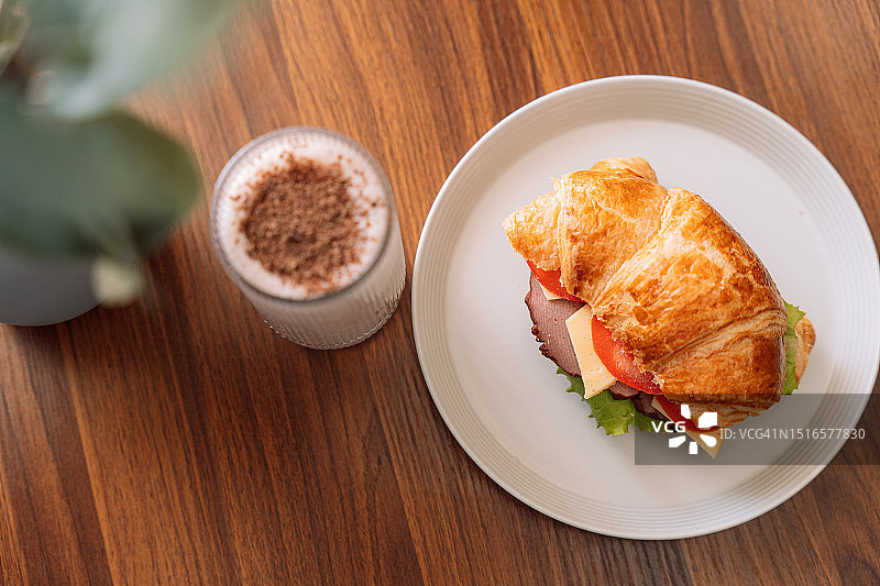 玻璃杯中的巧克力奶昔，旁边是盘子里有肉的羊角面包图片素材