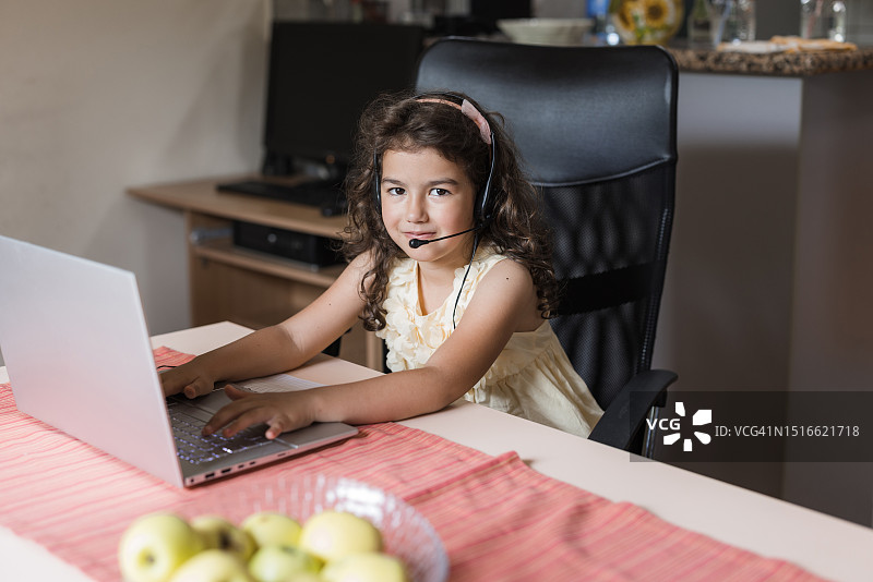 戴无线耳机使用笔记本电脑的女孩图片素材