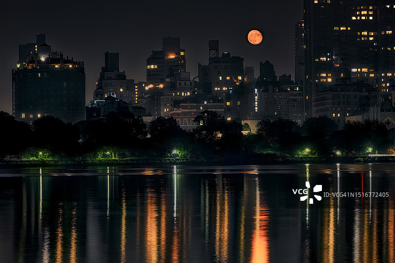 上弦月升起在曼哈顿东区，倒映在中央公园的杰奎琳·肯尼迪·奥纳西斯水库中。图片素材