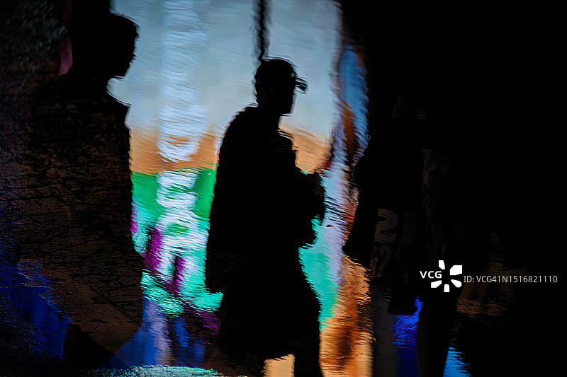 夜晚曼哈顿时代广场雨水坑中行人的倒影图片素材