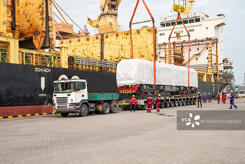 在林查班港使用港口重型起重机卸载项目货物，大型货船上的起重机正在装载新的柴油电力机车图片素材
