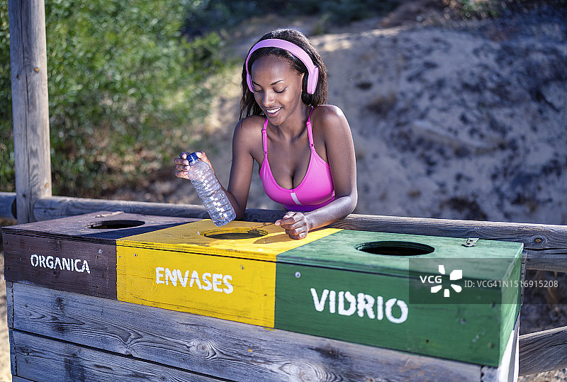 在海滩回收塑料瓶的漂亮黑人女孩，关注环保的年轻人图片素材