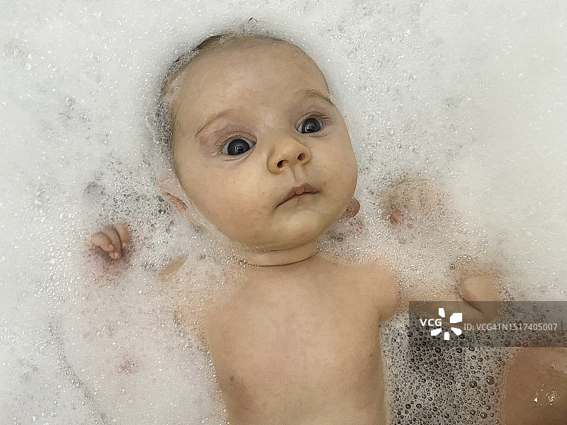 在泡泡浴中保持警觉的新生儿图片素材
