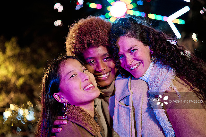 夜晚在户外对着镜头微笑的多民族朋友图片素材