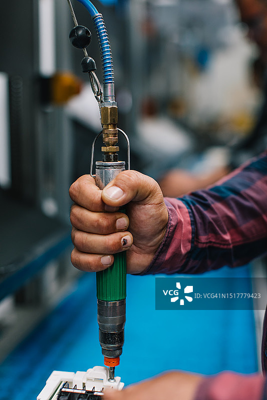 工厂里使用气动扳手的产业工人图片素材