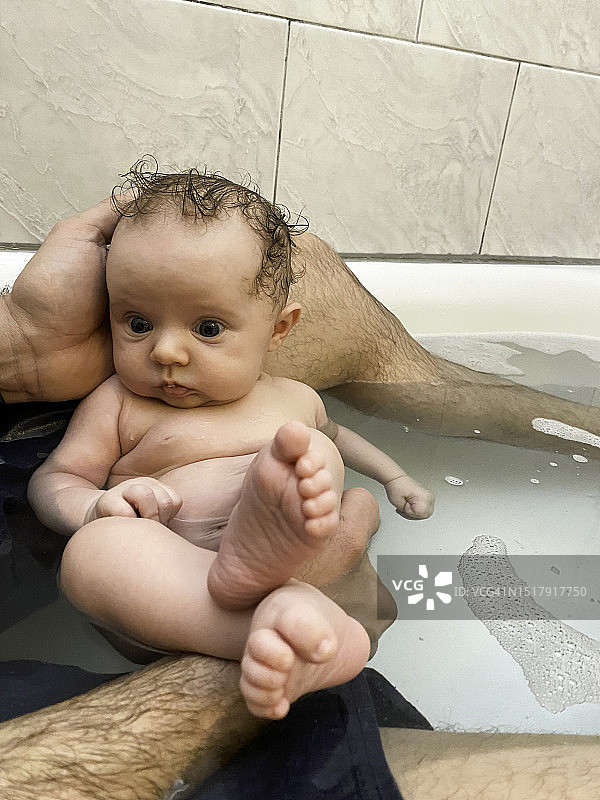 父亲第一次在浴缸里温柔地抱着新生婴儿图片素材