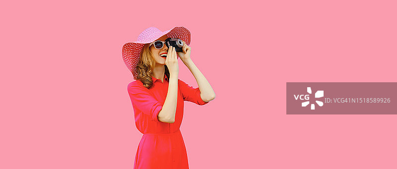 年轻女摄影师戴草帽在阳光下微笑，手持胶片相机图片素材