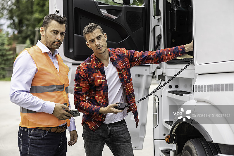 穿橙色背心的交通检查员检查卡车的气动悬架图片素材