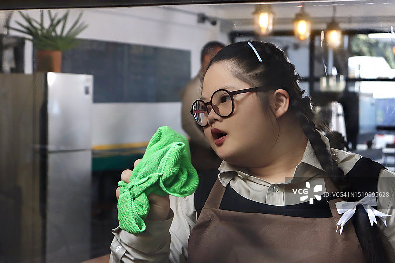 患有唐氏综合征的女服务员在咖啡馆擦拭窗户图片素材
