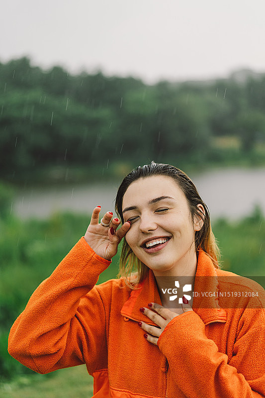 在夏日雨中穿着橙色毛衣的年轻女孩肖像图片素材