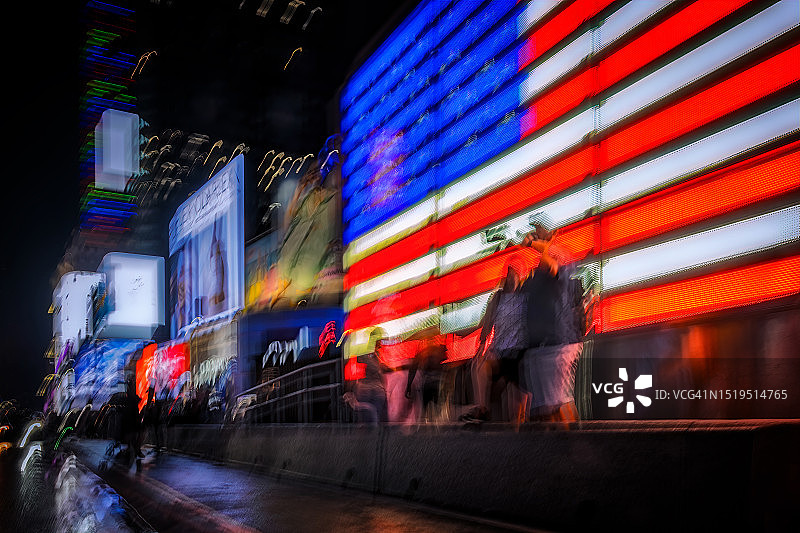 夜晚时代广场大型美国国旗前的人群动态模糊图片素材