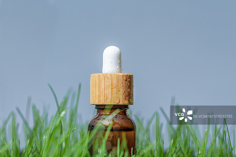 带滴管的琥珀色精油瓶，配有绿色草地图片素材